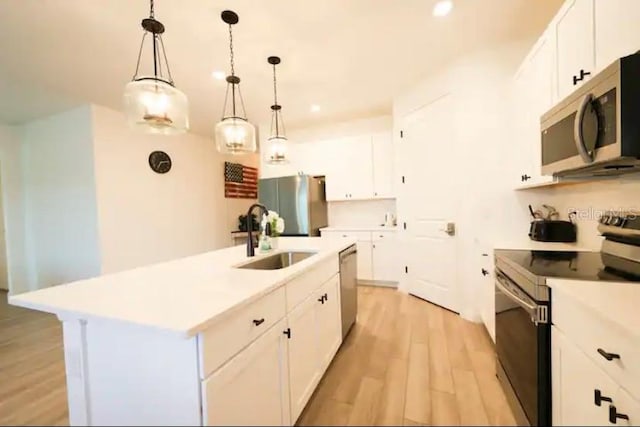 kitchen featuring stainless steel appliances, decorative light fixtures, light hardwood / wood-style flooring, a center island with sink, and white cabinets