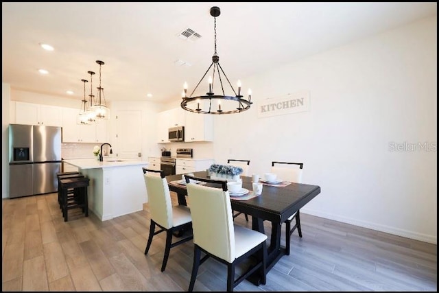 dining area with a chandelier, light hardwood / wood-style floors, and sink