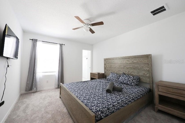 carpeted bedroom featuring ceiling fan and a textured ceiling