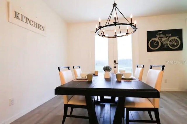 dining space featuring wood-type flooring and an inviting chandelier