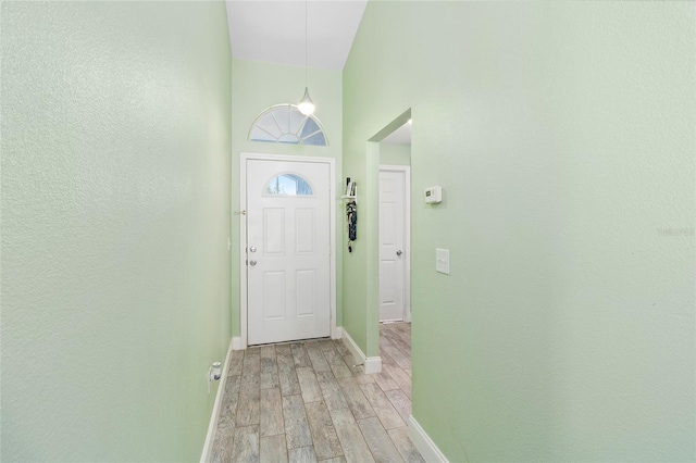 doorway featuring a high ceiling and light hardwood / wood-style flooring