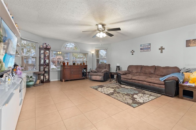 tiled living room featuring ceiling fan, a textured ceiling, and a wealth of natural light