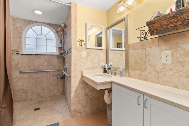 bathroom featuring tile patterned flooring, a textured ceiling, sink, and tile walls