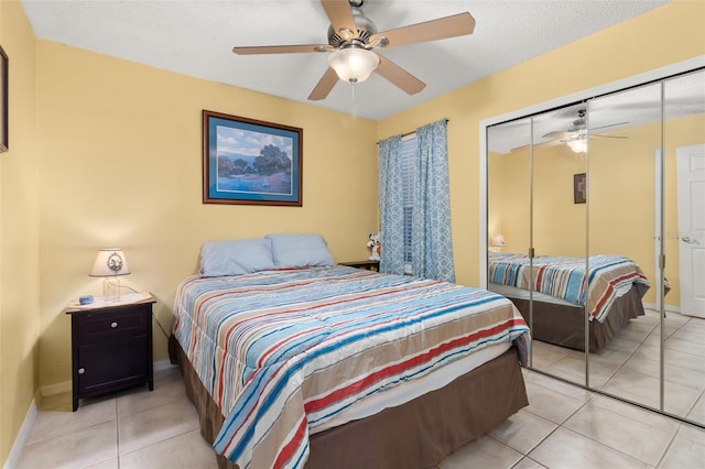 bedroom featuring ceiling fan, light tile patterned floors, a textured ceiling, and a closet