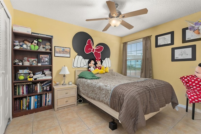 bedroom with light tile patterned floors, a textured ceiling, a closet, and ceiling fan