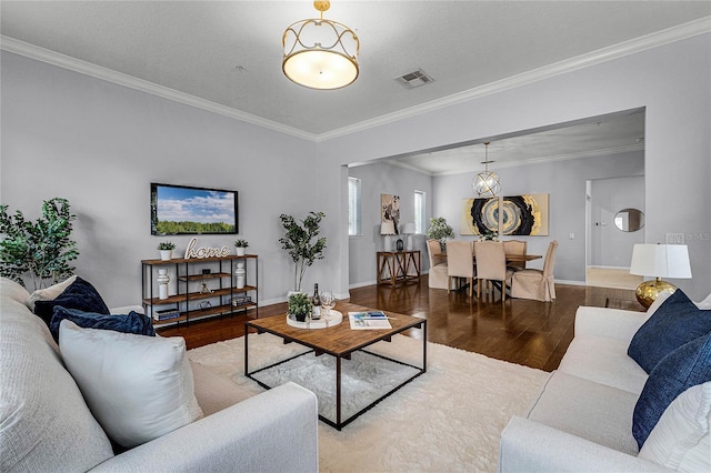 living room featuring wood-type flooring, ornamental molding, and a notable chandelier