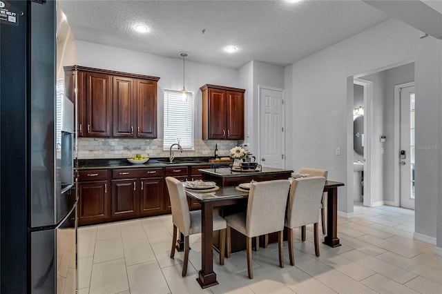 kitchen with a textured ceiling, refrigerator, decorative light fixtures, and sink