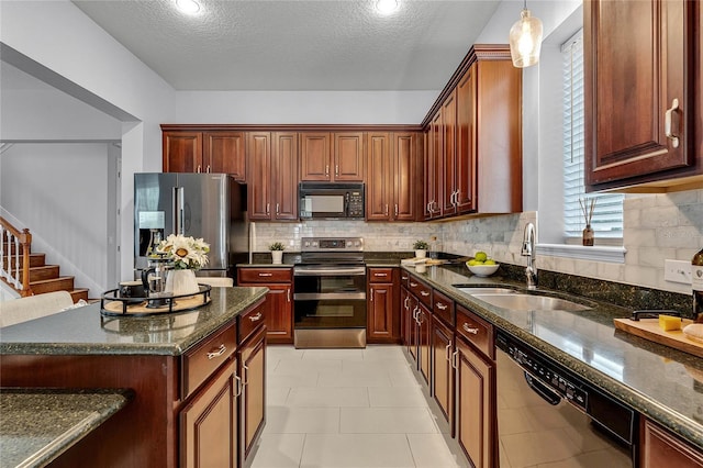 kitchen featuring pendant lighting, sink, decorative backsplash, a textured ceiling, and appliances with stainless steel finishes