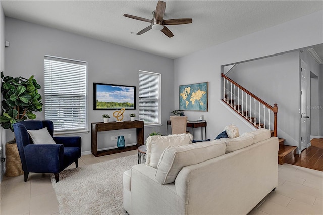 living room featuring ceiling fan, light hardwood / wood-style floors, and a textured ceiling