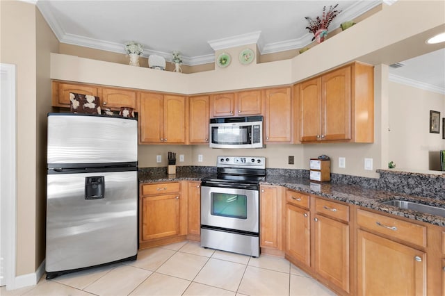 kitchen featuring light tile patterned floors, dark stone counters, appliances with stainless steel finishes, crown molding, and a sink