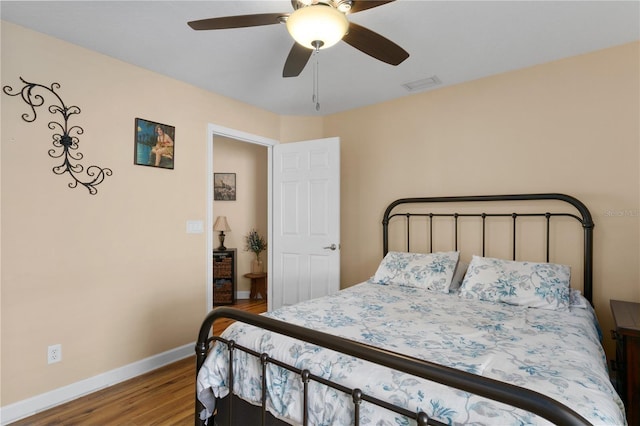 bedroom featuring a ceiling fan, wood finished floors, visible vents, and baseboards