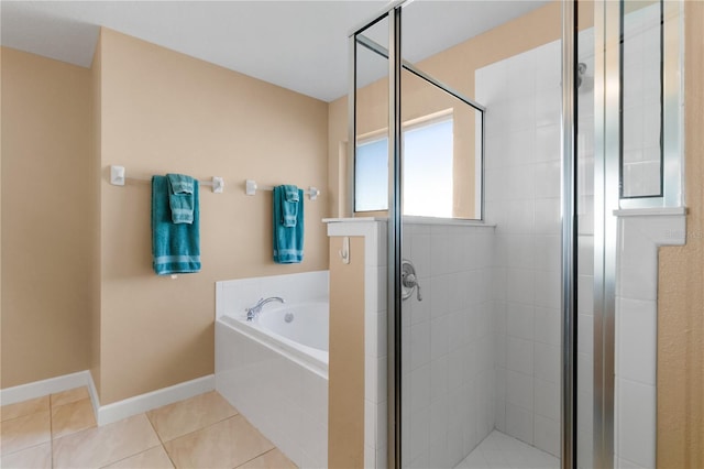 bathroom with a garden tub, a shower stall, baseboards, and tile patterned flooring