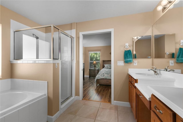 bathroom with double vanity, a stall shower, a sink, ensuite bath, and tile patterned flooring