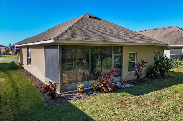 back of house featuring a shingled roof, a sunroom, a yard, and stucco siding