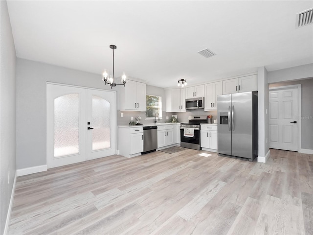 kitchen with french doors, hanging light fixtures, stainless steel appliances, light hardwood / wood-style floors, and white cabinets