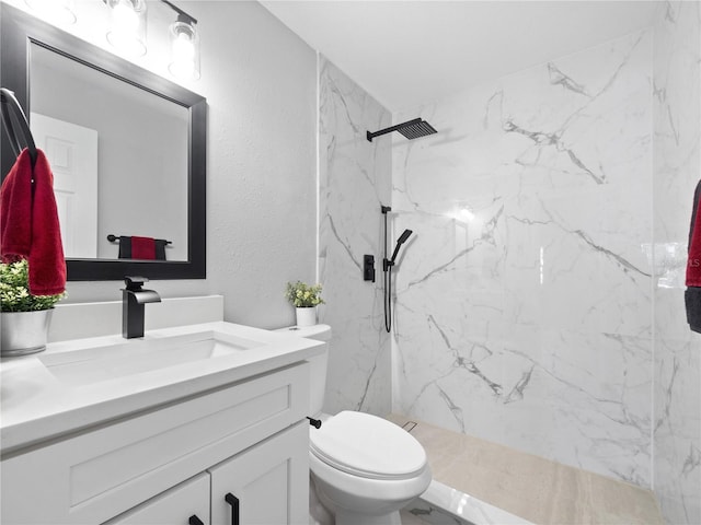 bathroom with vanity, toilet, and tiled shower