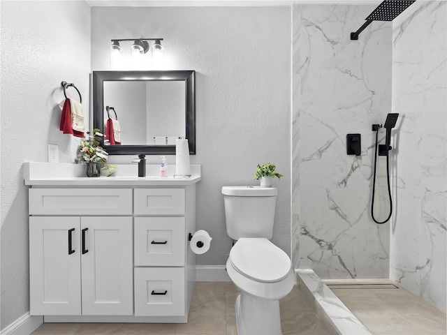 bathroom featuring tile patterned floors, toilet, vanity, and tiled shower