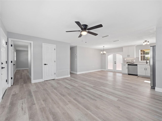 unfurnished living room featuring french doors, ceiling fan with notable chandelier, and light hardwood / wood-style flooring