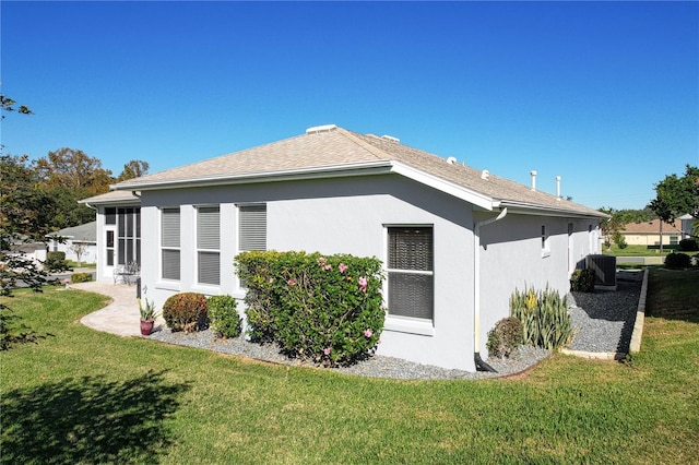 view of side of property with a lawn and central AC unit