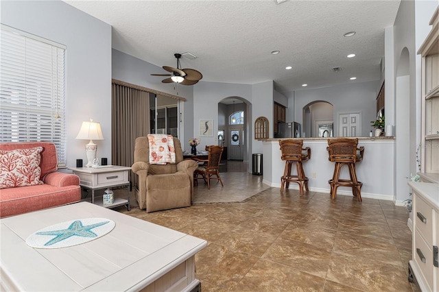 living room featuring ceiling fan and a textured ceiling