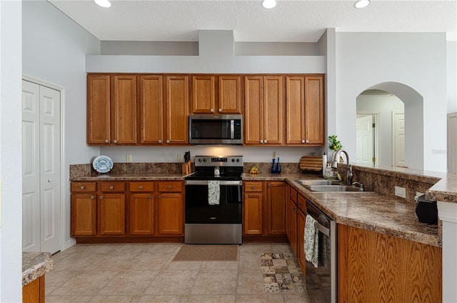 kitchen featuring sink, light tile patterned floors, stainless steel appliances, and a textured ceiling