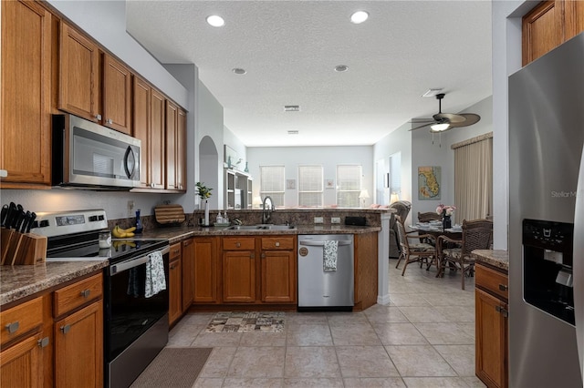 kitchen with kitchen peninsula, a textured ceiling, stainless steel appliances, ceiling fan, and sink