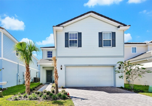 view of front of property featuring a garage and cooling unit