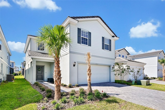 view of front of house featuring a garage, a front lawn, and central air condition unit