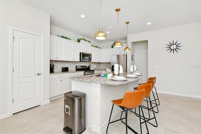 kitchen featuring white cabinetry, a kitchen island with sink, hanging light fixtures, and appliances with stainless steel finishes