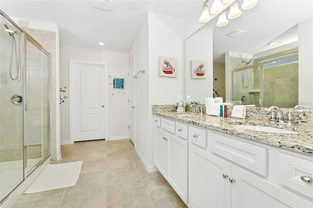 bathroom with a shower with door, vanity, and tile patterned flooring