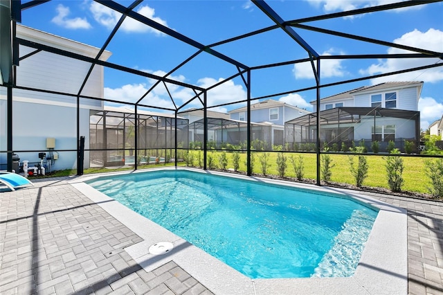 view of swimming pool featuring glass enclosure, a patio area, and a yard