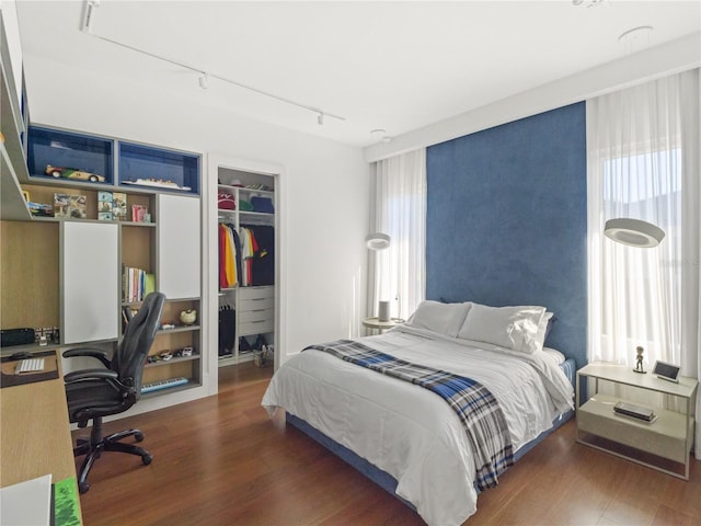 bedroom with a closet, rail lighting, and dark wood-type flooring