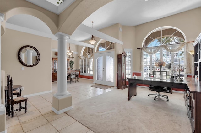 entryway featuring light carpet, french doors, decorative columns, and a notable chandelier