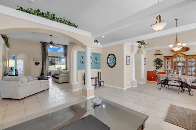 tiled living room with ceiling fan with notable chandelier and ornate columns