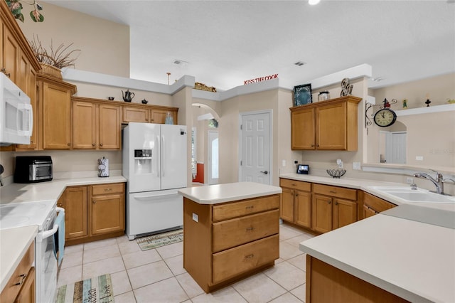 kitchen with light tile patterned floors, white appliances, a center island, and sink