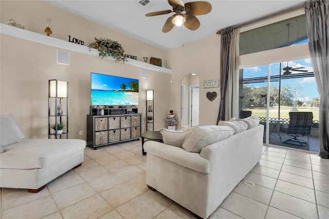 tiled living room with ceiling fan and a towering ceiling