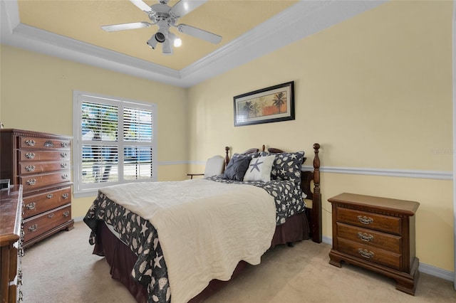 carpeted bedroom featuring ceiling fan, crown molding, and a tray ceiling