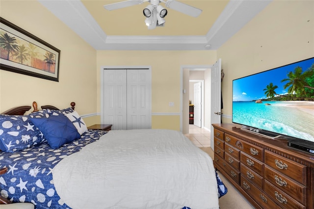 bedroom featuring ceiling fan, ornamental molding, a tray ceiling, and a closet