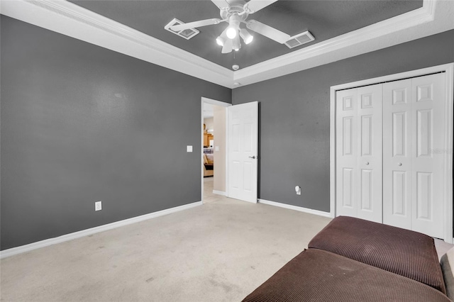 unfurnished room with a tray ceiling, ceiling fan, light colored carpet, and ornamental molding