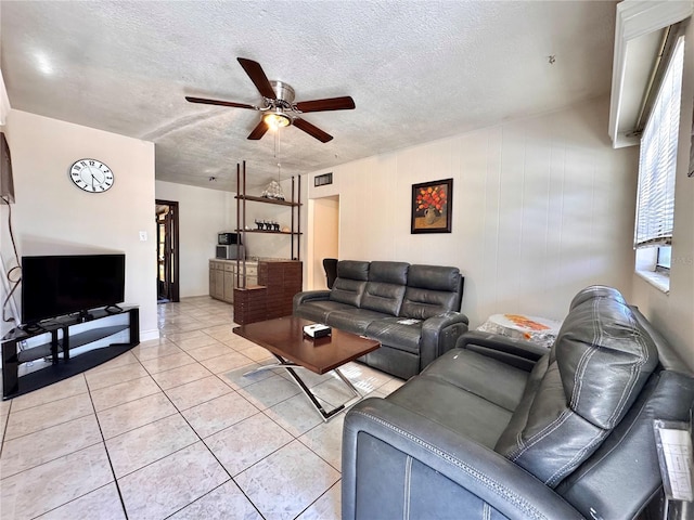 tiled living room featuring ceiling fan, wood walls, and a textured ceiling