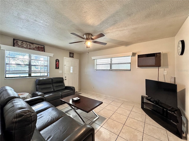 living room featuring a wall unit AC, ceiling fan, light tile patterned floors, and a textured ceiling