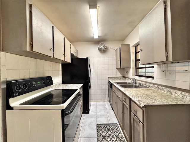 kitchen with black fridge, sink, light tile patterned floors, electric range, and tile walls