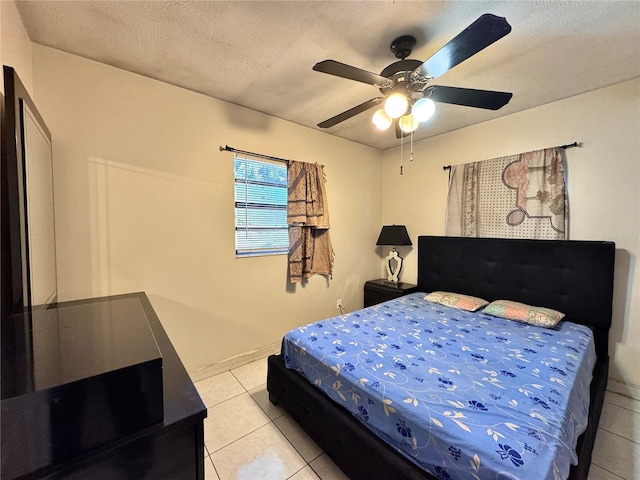 bedroom featuring ceiling fan, light tile patterned flooring, and a textured ceiling