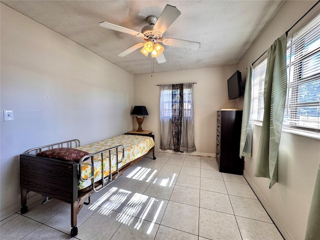 bedroom featuring multiple windows, light tile patterned floors, a textured ceiling, and ceiling fan