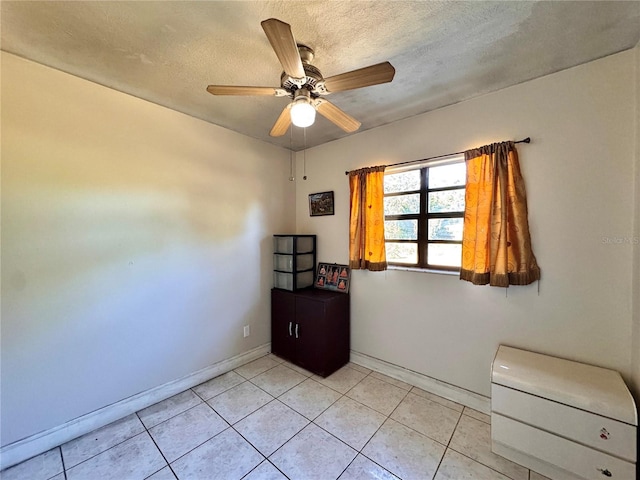 tiled empty room featuring ceiling fan and a textured ceiling