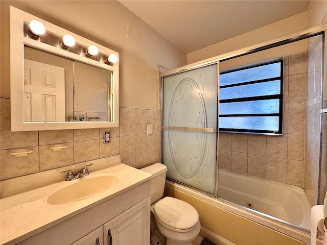 full bathroom featuring combined bath / shower with glass door, a textured ceiling, toilet, vanity, and tile walls