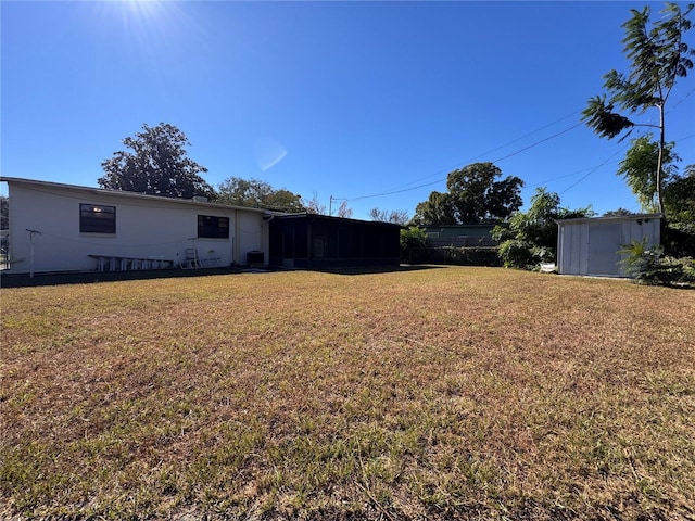 view of yard featuring a sunroom and a storage shed