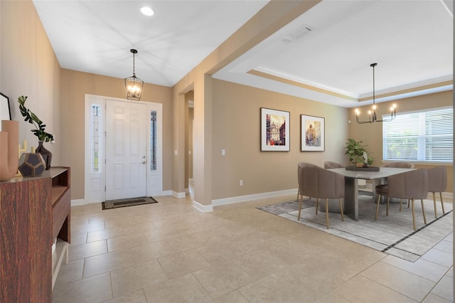 entryway featuring an inviting chandelier, a tray ceiling, and light tile patterned flooring