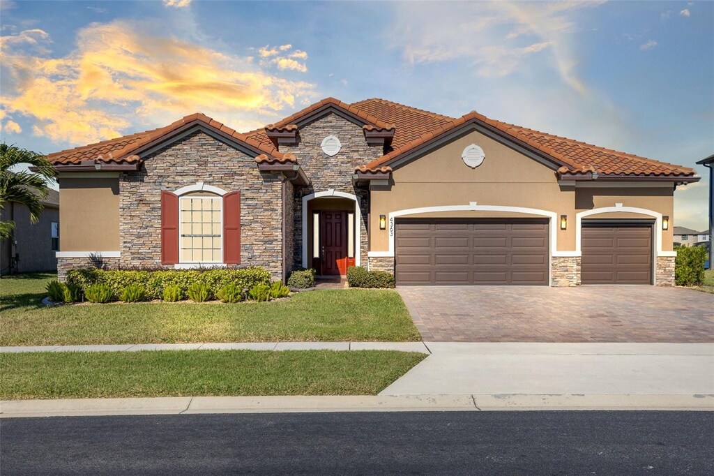 4363 Summer Breeze Way, Kissimmee, FL 34744 - mediterranean / spanish-style home featuring a garage and a lawn