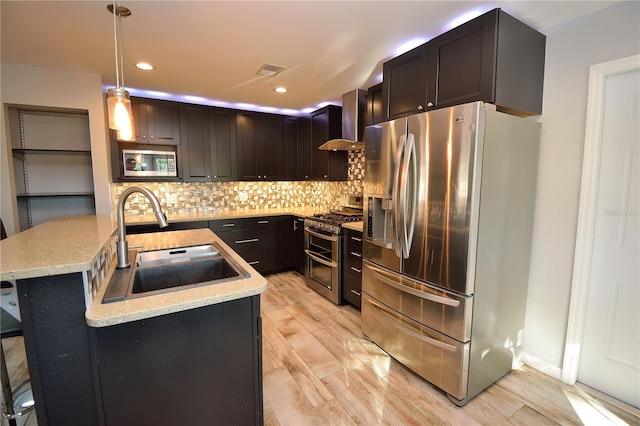 kitchen featuring pendant lighting, sink, wall chimney range hood, appliances with stainless steel finishes, and a kitchen breakfast bar